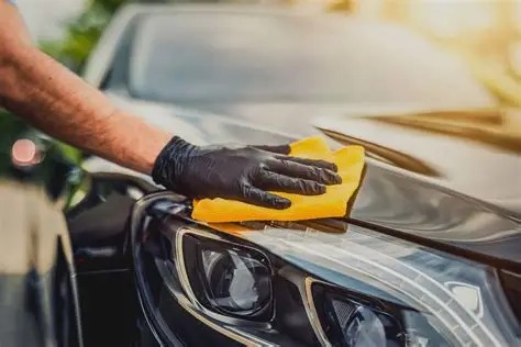 Hand-wiping a freshly polished car hood with a microfiber towel